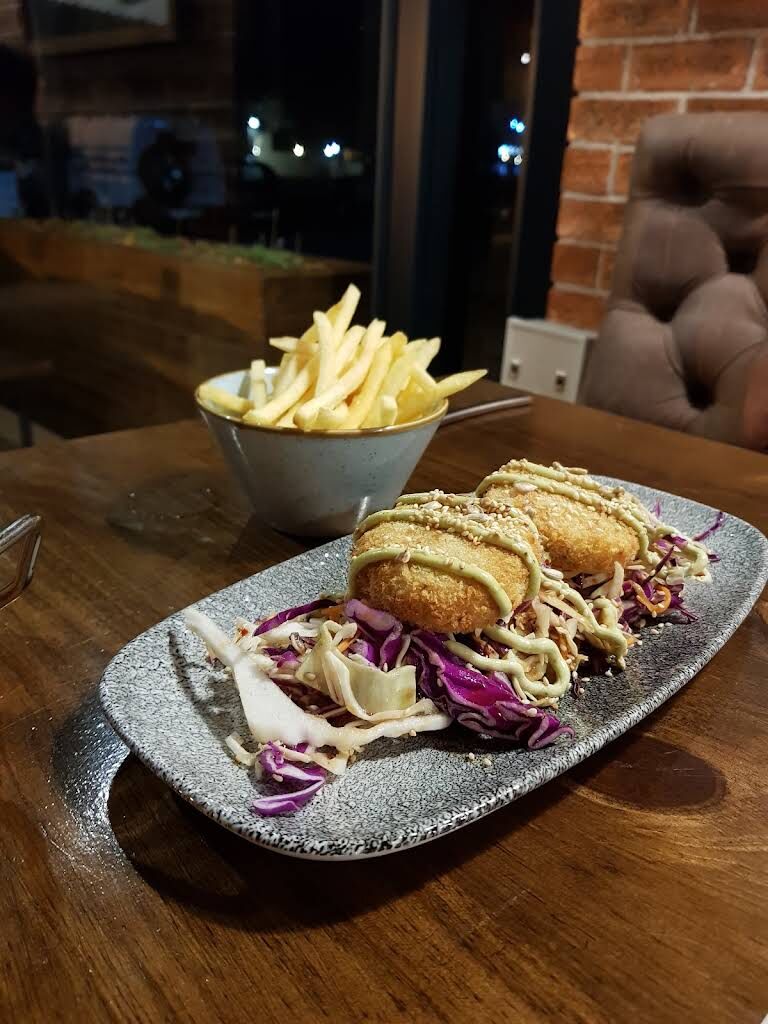 Crumbed cakes on slaw with a bowl of chips